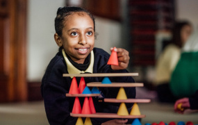 Young girl in school uniform playing with a STEM toy.